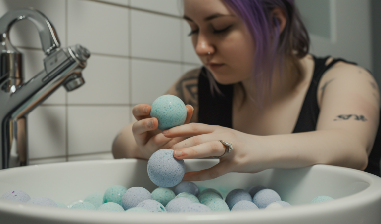 A photo of a colorful bath bomb surrounded by bubbles in a bathtub. The bath bomb is spherical and seems to be made of various layers of different colors.